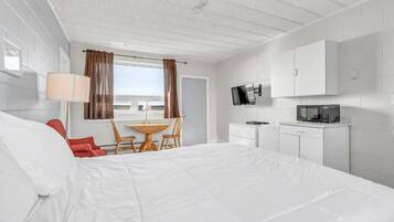 A hotel room with a large bed, a desk, a chair, a television, and a microwave.