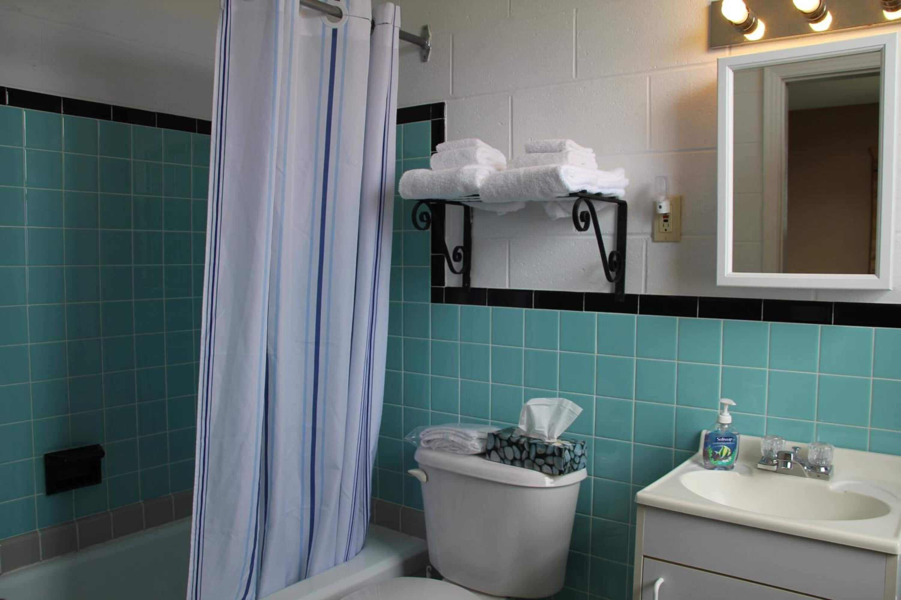 Un bagno con il water, un lavandino e uno specchio sopra il lavandino.