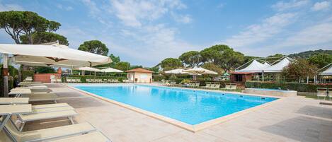 En säsongsöppen utomhuspool, parasoller och solstolar