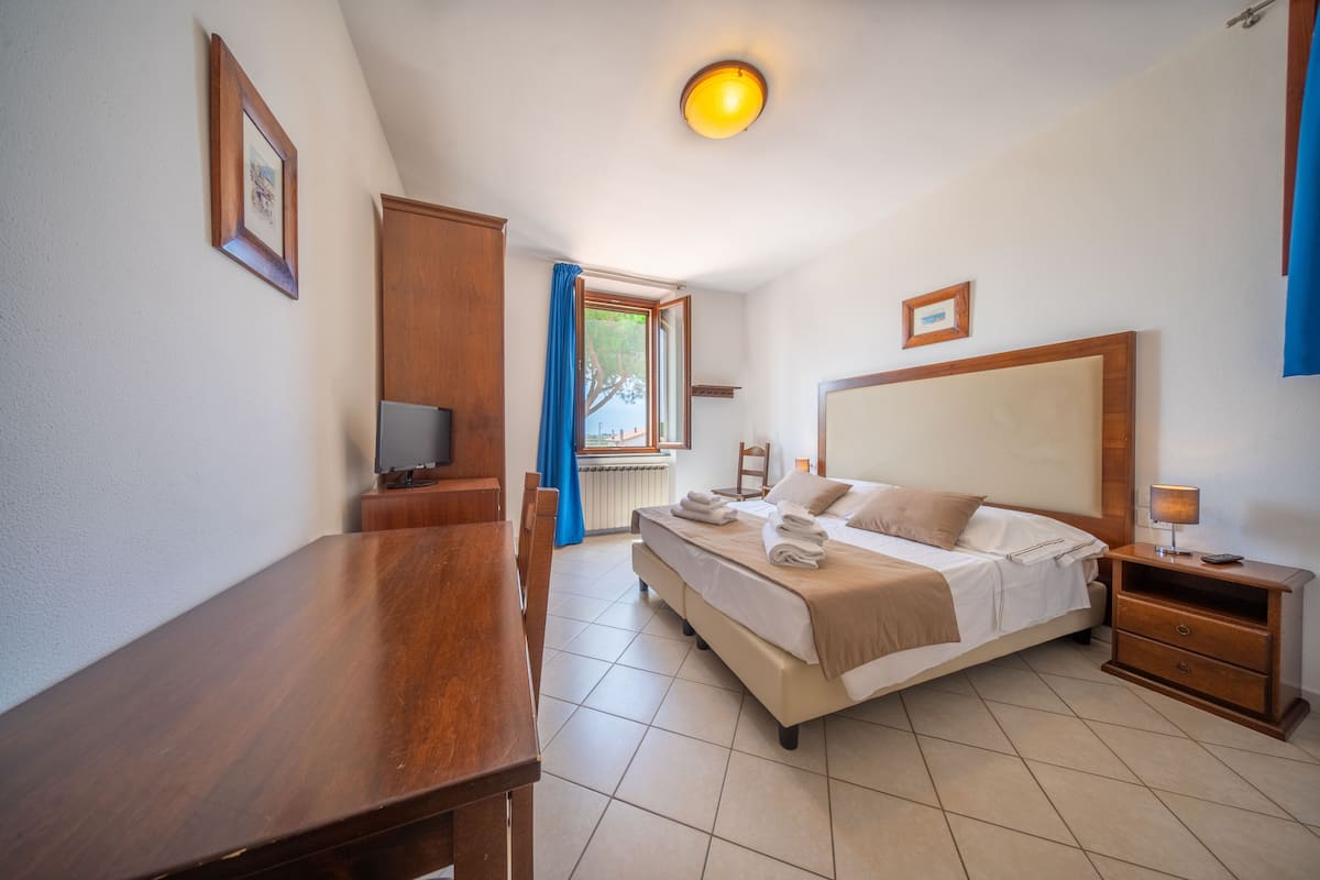 A bedroom with a bed, bedside table, and a desk with a chair.