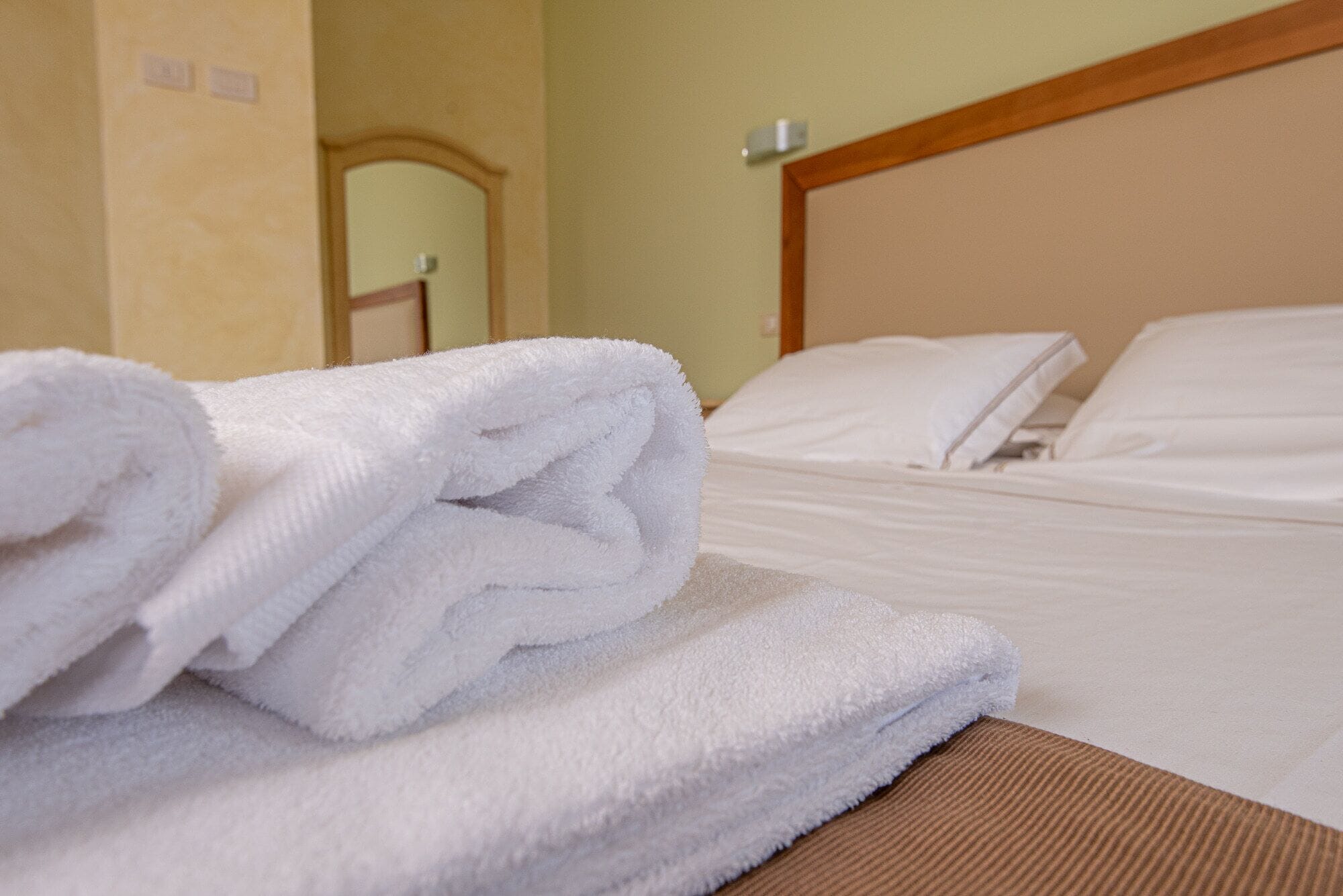 Una cama bien tendida con sábanas blancas y cabecera de madera.