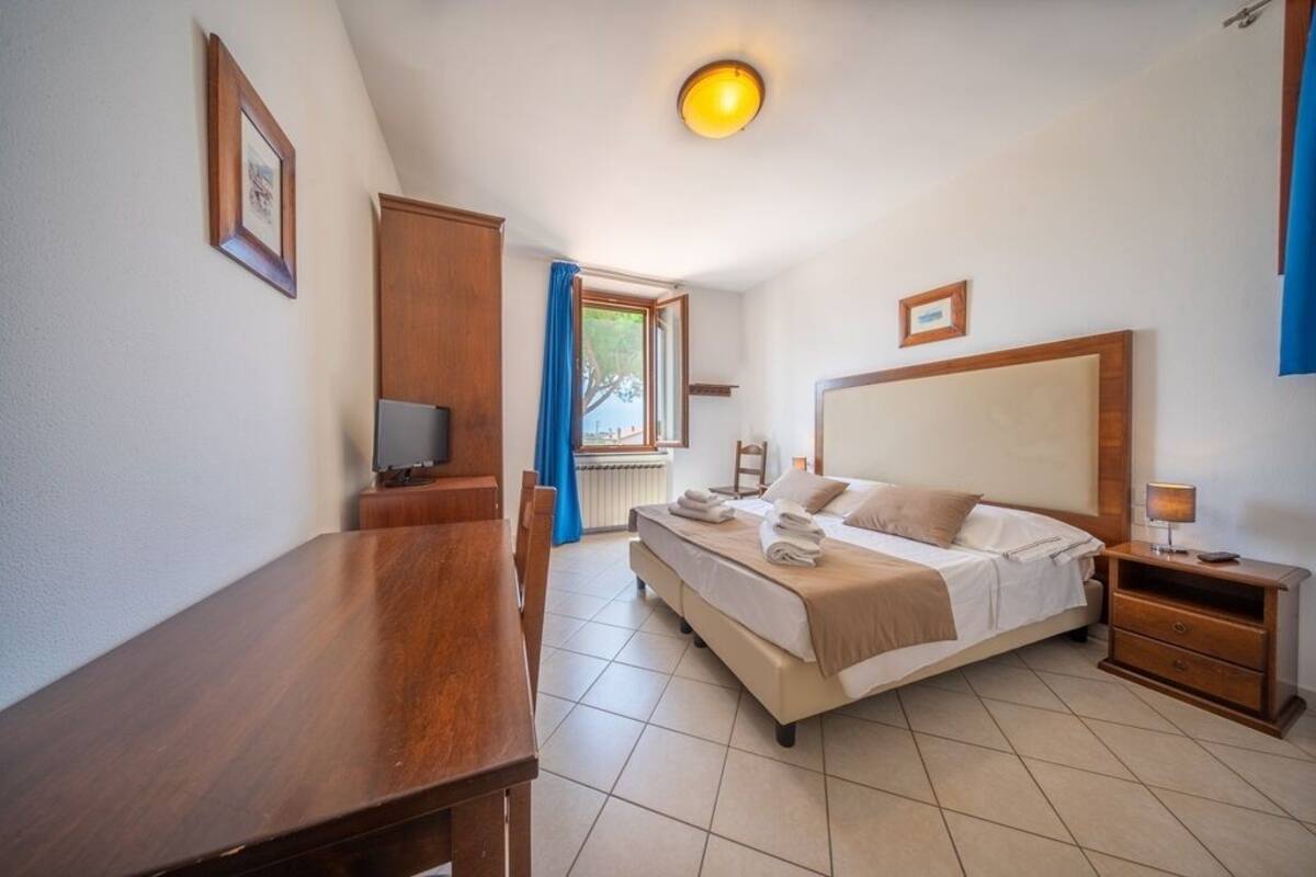 A bedroom with a bed, bedside table, and a desk with a chair.