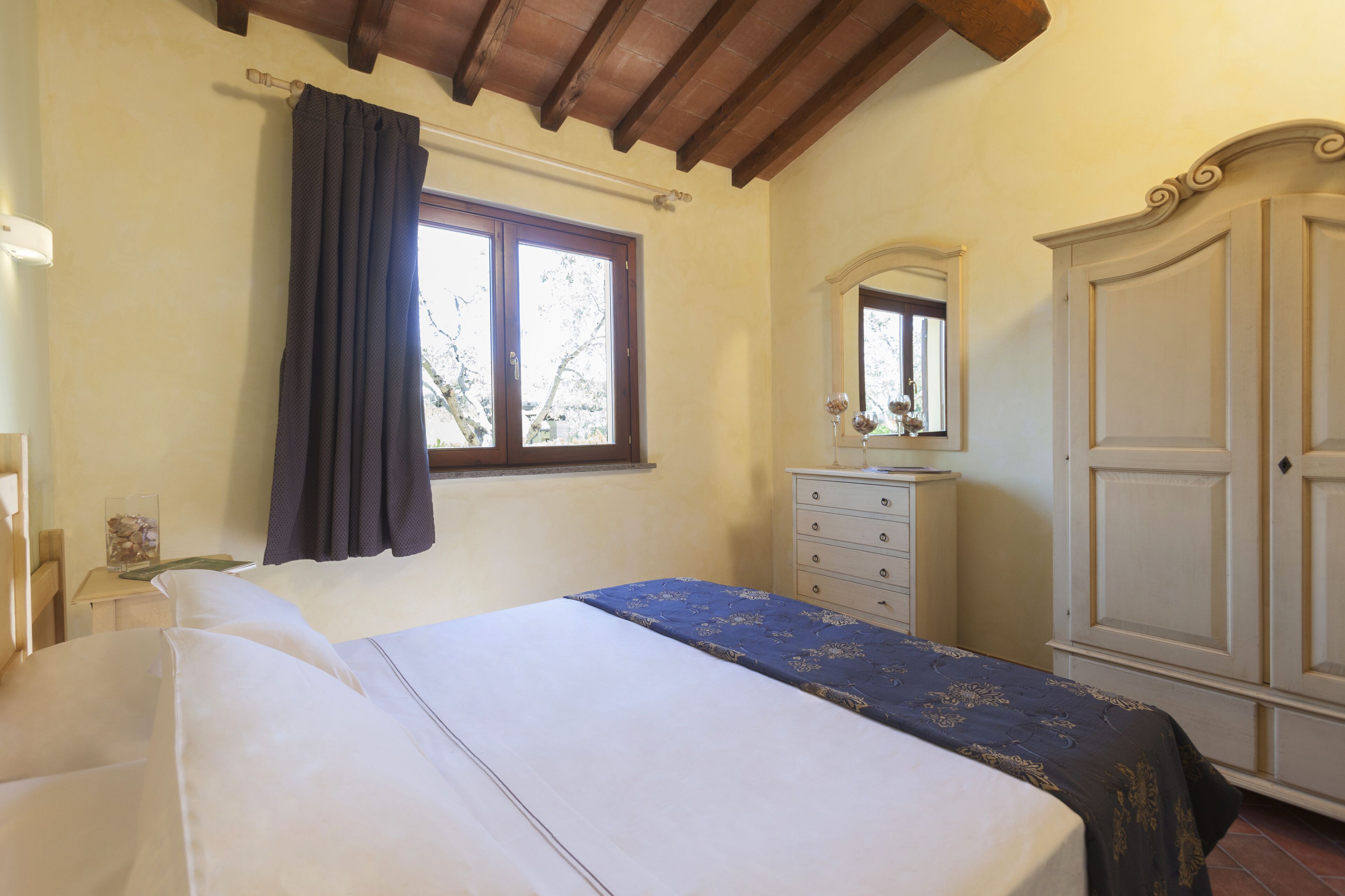 A bedroom with a bed, a dresser, a mirror, and a wardrobe.