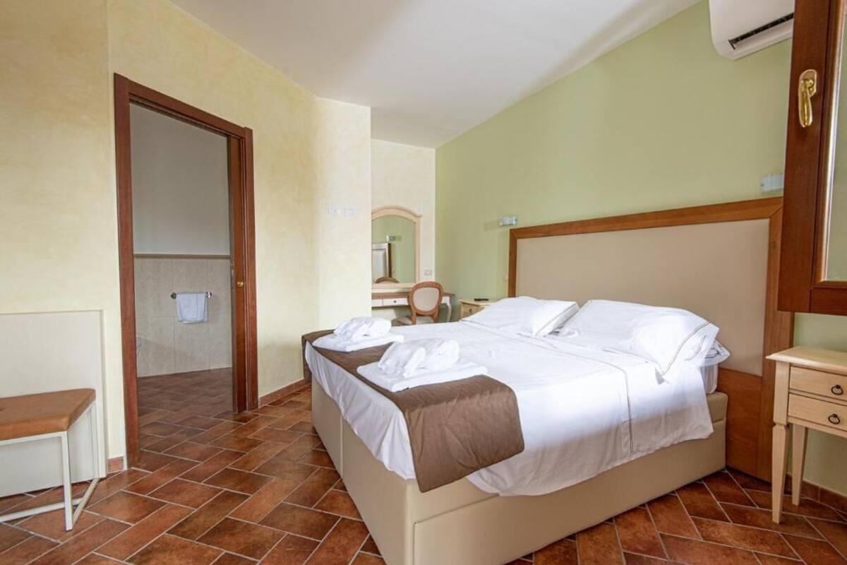 A hotel room with a bed, a bedside table, a chair, and a small desk.