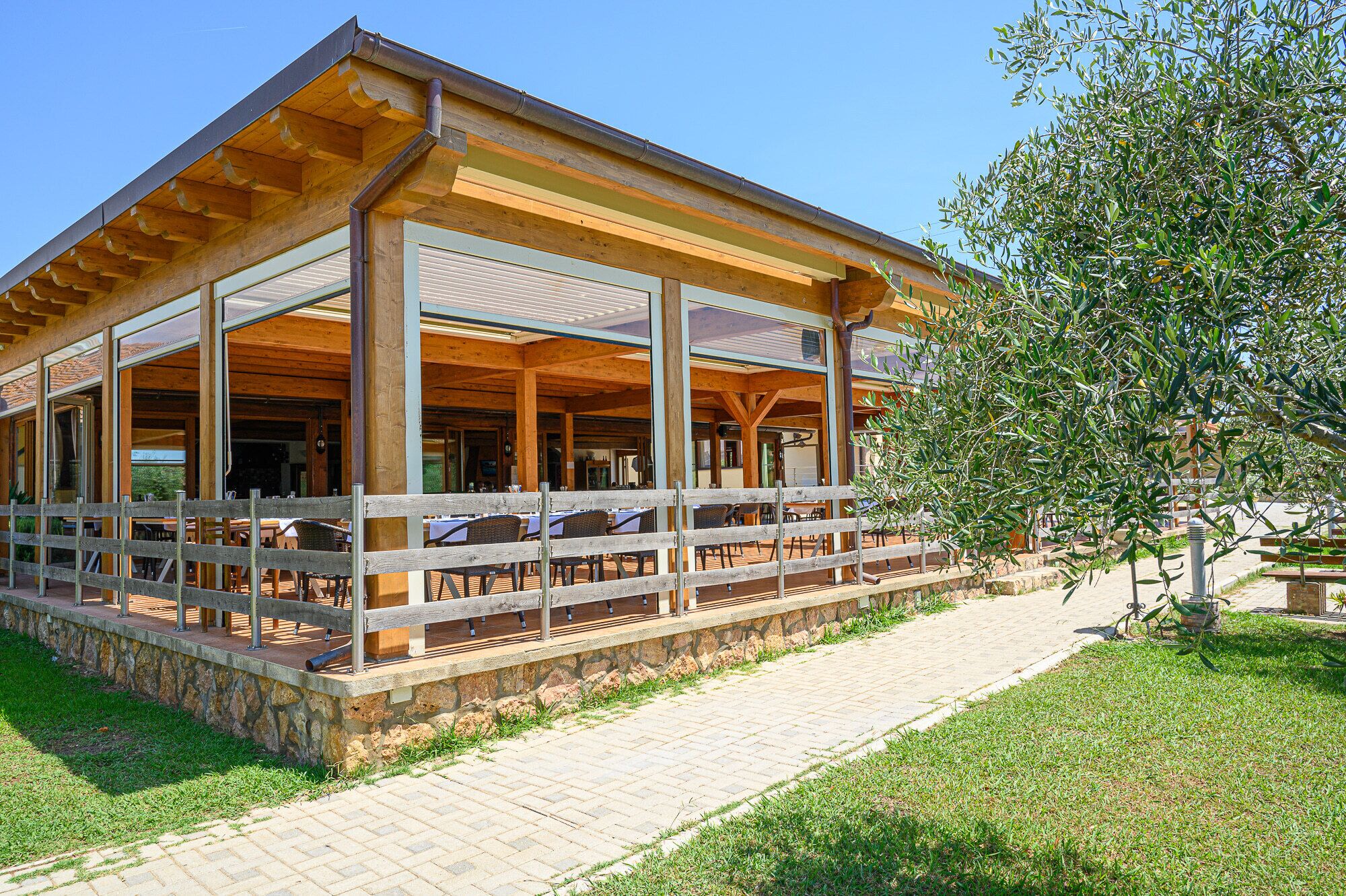 A wooden building with a covered patio area, stone steps, and a grassy area.