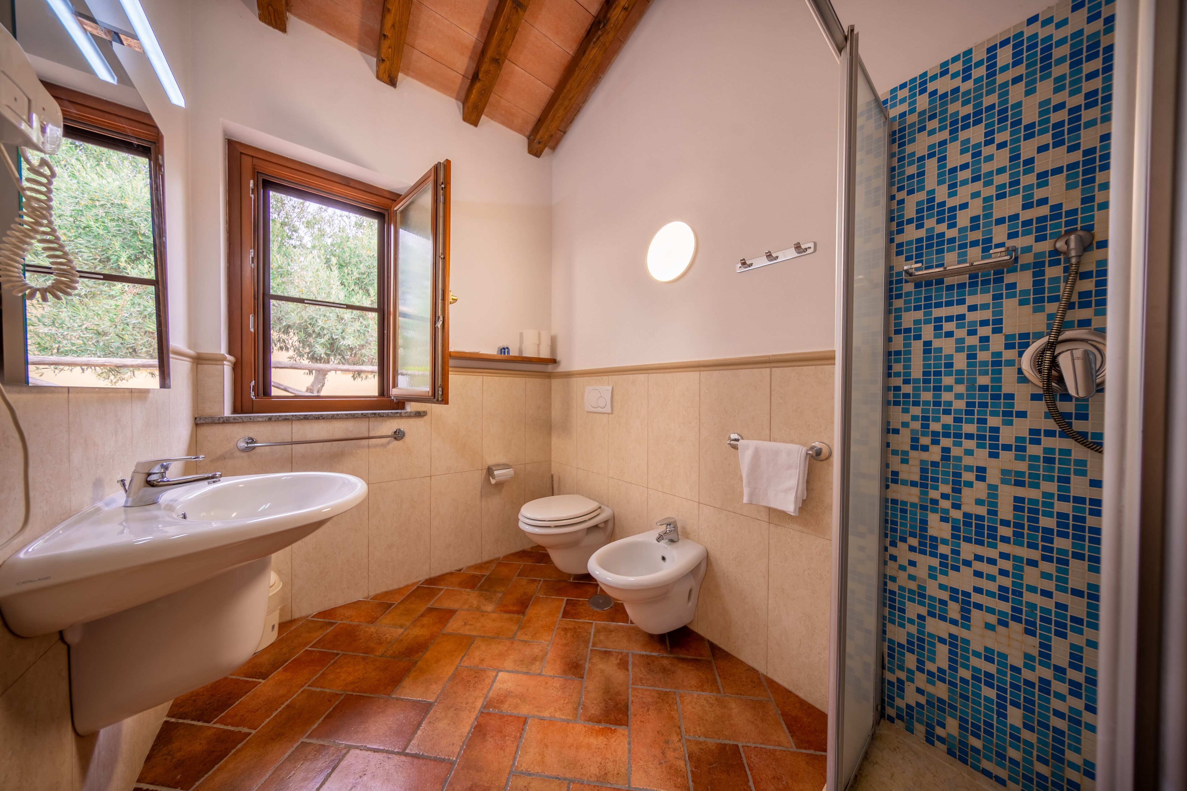 Une salle de bain équipée d’un lavabo, de toilettes, d’un bidet et d’une douche aux carreaux en mosaïque.