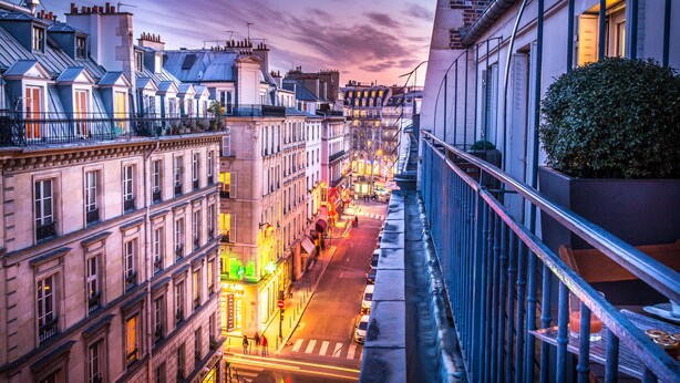 A city street at dusk with buildings on either side and a pedestrian walkway. - Hotel Opera Marigny (Paris)