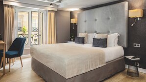 A large bed with a grey upholstered headboard, a bedside table, and a chair. - Hotel Opera Marigny (Paris)