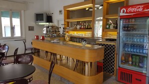 Un espace bar avec un comptoir, des sièges et un réfrigérateur à boissons, notamment des Coca-Cola.