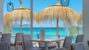 A restaurant with a view of the ocean, featuring thatched umbrellas and modern chairs.