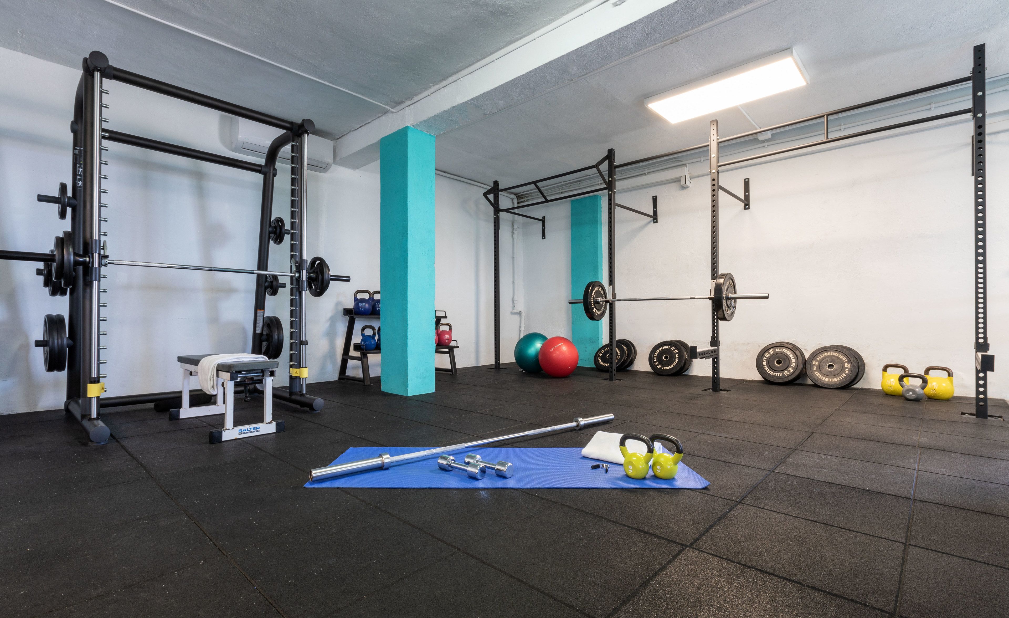 A gym with weightlifting equipment, a bench, and exercise balls.