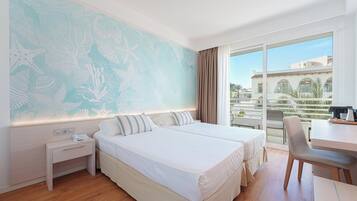 A hotel room with two beds, a desk, and a large window with a view of buildings.