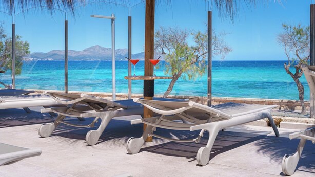 A beachside lounge with sun loungers and a view of the sea.