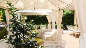 An outdoor patio area with white wicker furniture under a canopy. - Polo BeYou Hotel (Riccione)