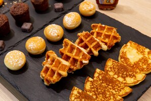 Una variedad de pasteles, incluyendo gofres y tartas redondas, sobre una tabla de pizarra.