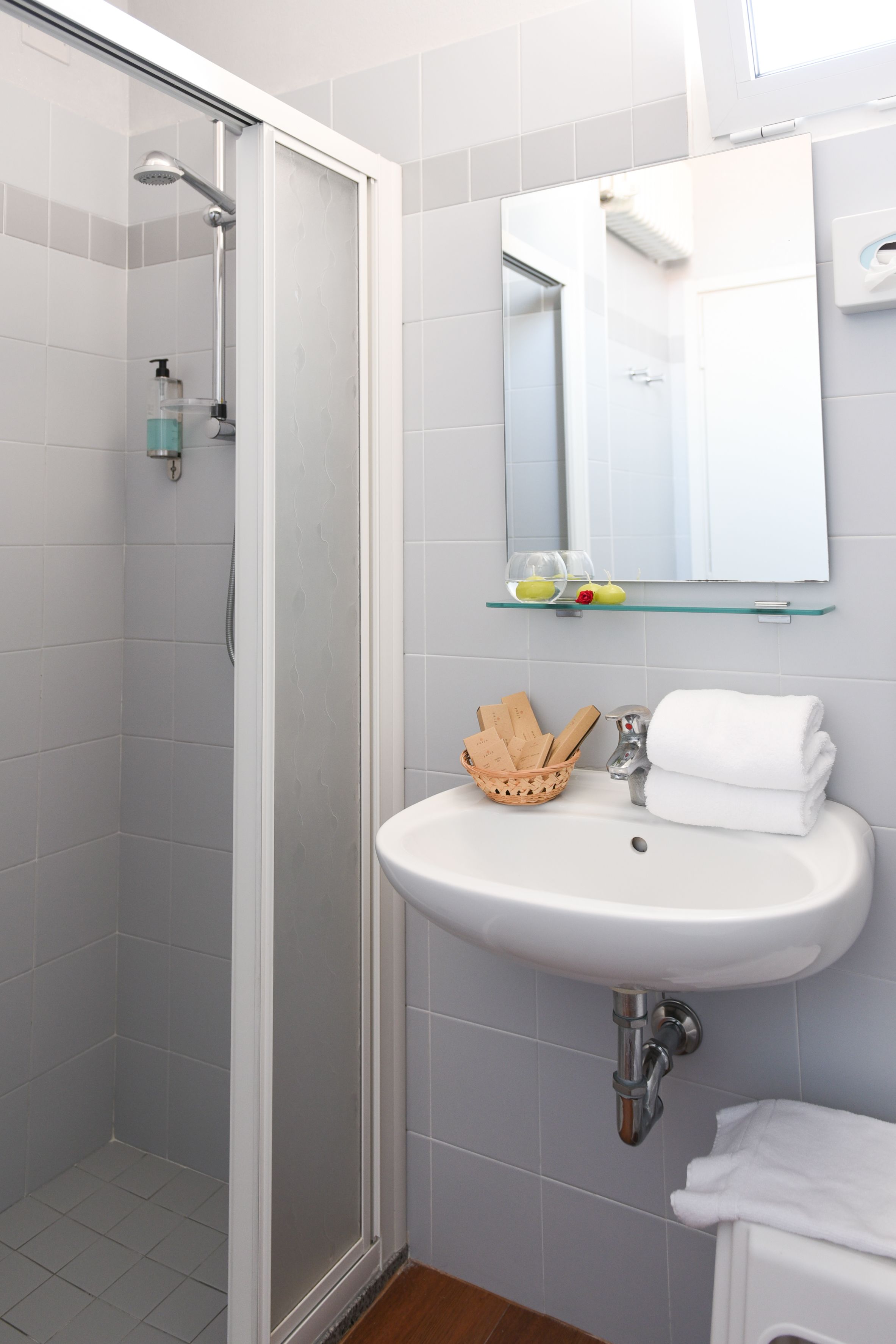 Un bagno con doccia, lavandino e specchio.