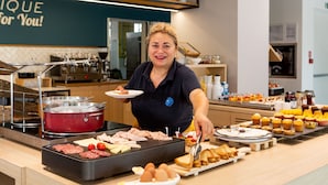 A buffet setup with various food items and a person serving. - Polo BeYou Hotel (Riccione)