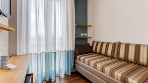 A modern living room with a sofa, a wooden table, and a TV. - Polo BeYou Hotel (Riccione)