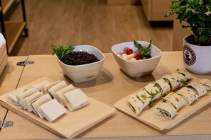 Una mesa de madera con sándwiches ordenados y un cuenco de semillas negras.