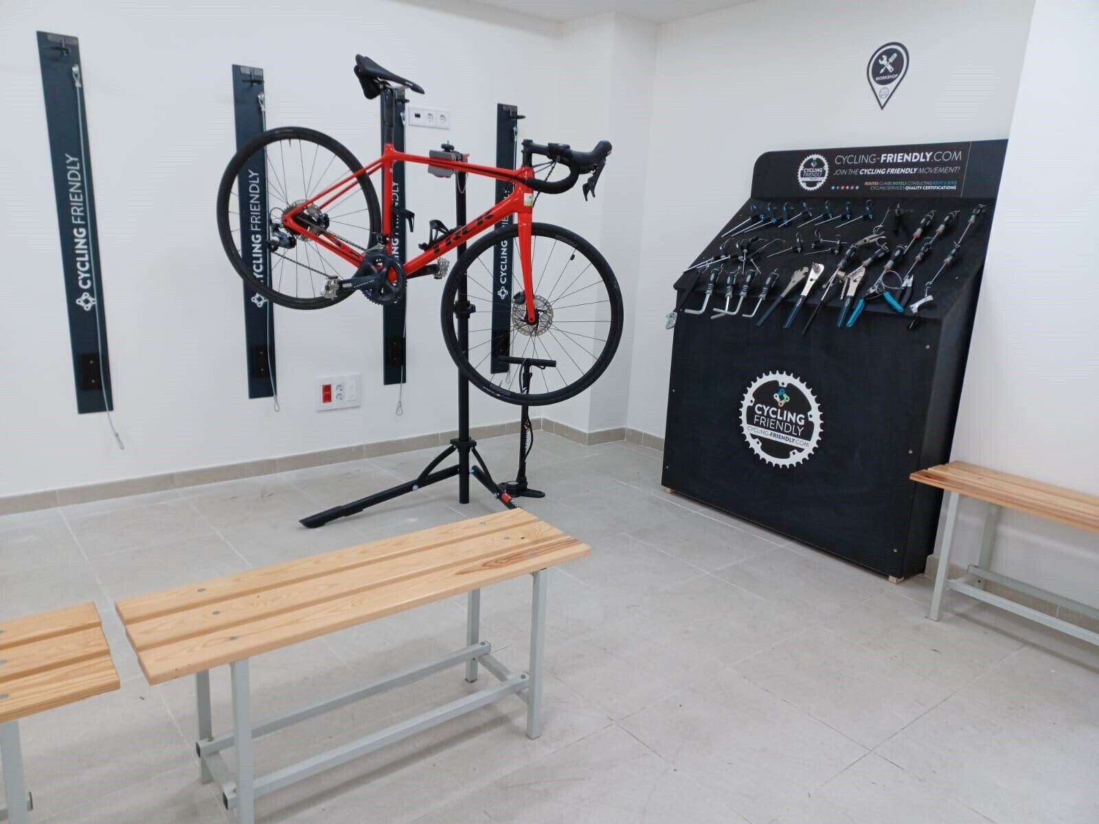 Een kamer met een op een standaard gemonteerde fiets, een verzameling fietsonderhoudsgereedschap en houten banken.