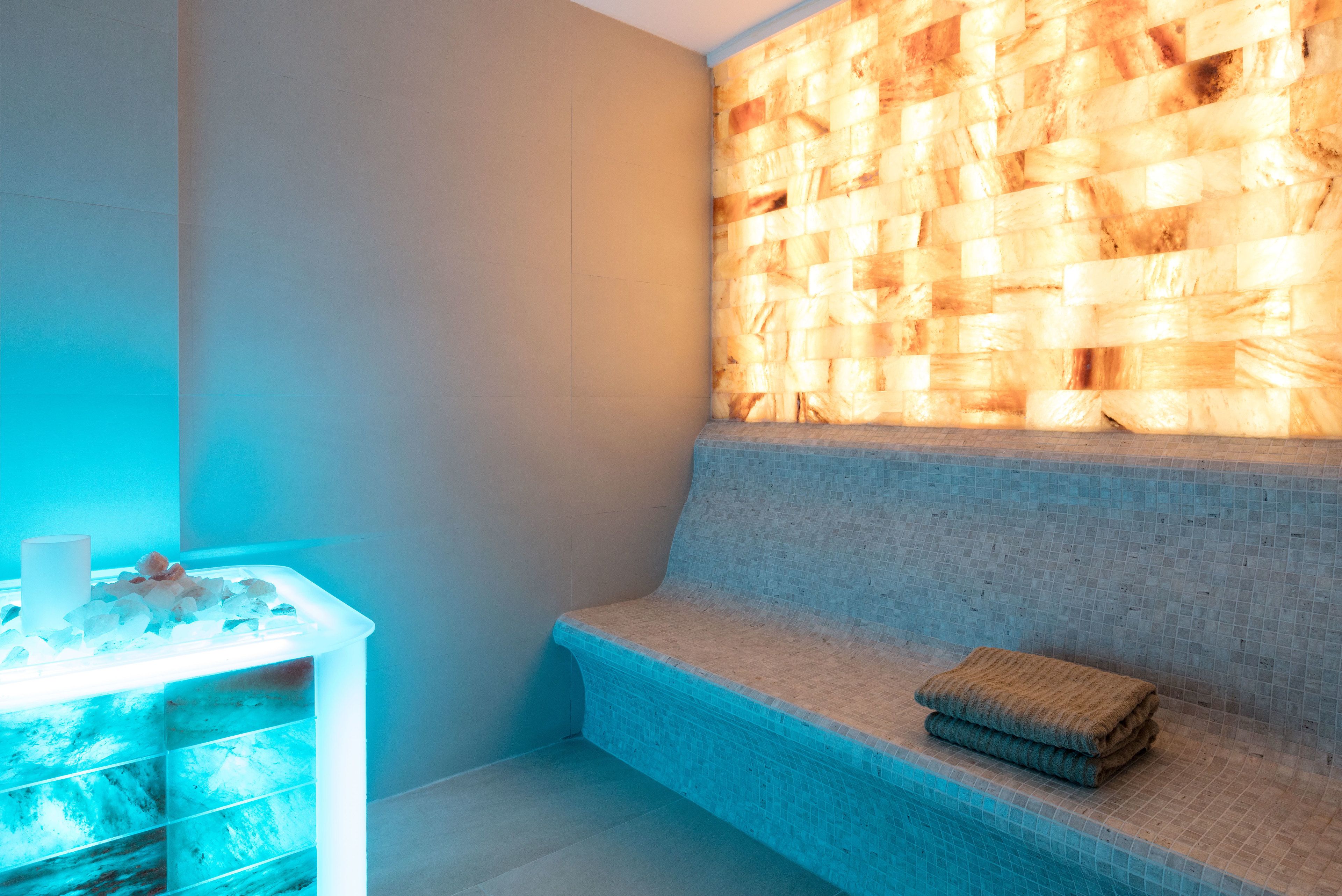 Ein Wellnessbereich mit Sitzbank und einer beheizten Steinwand.
