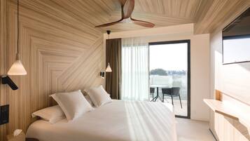 Una habitación de hotel moderna con una cama grande, un ventilador de techo y vistas a la ciudad a través de amplios ventanales.