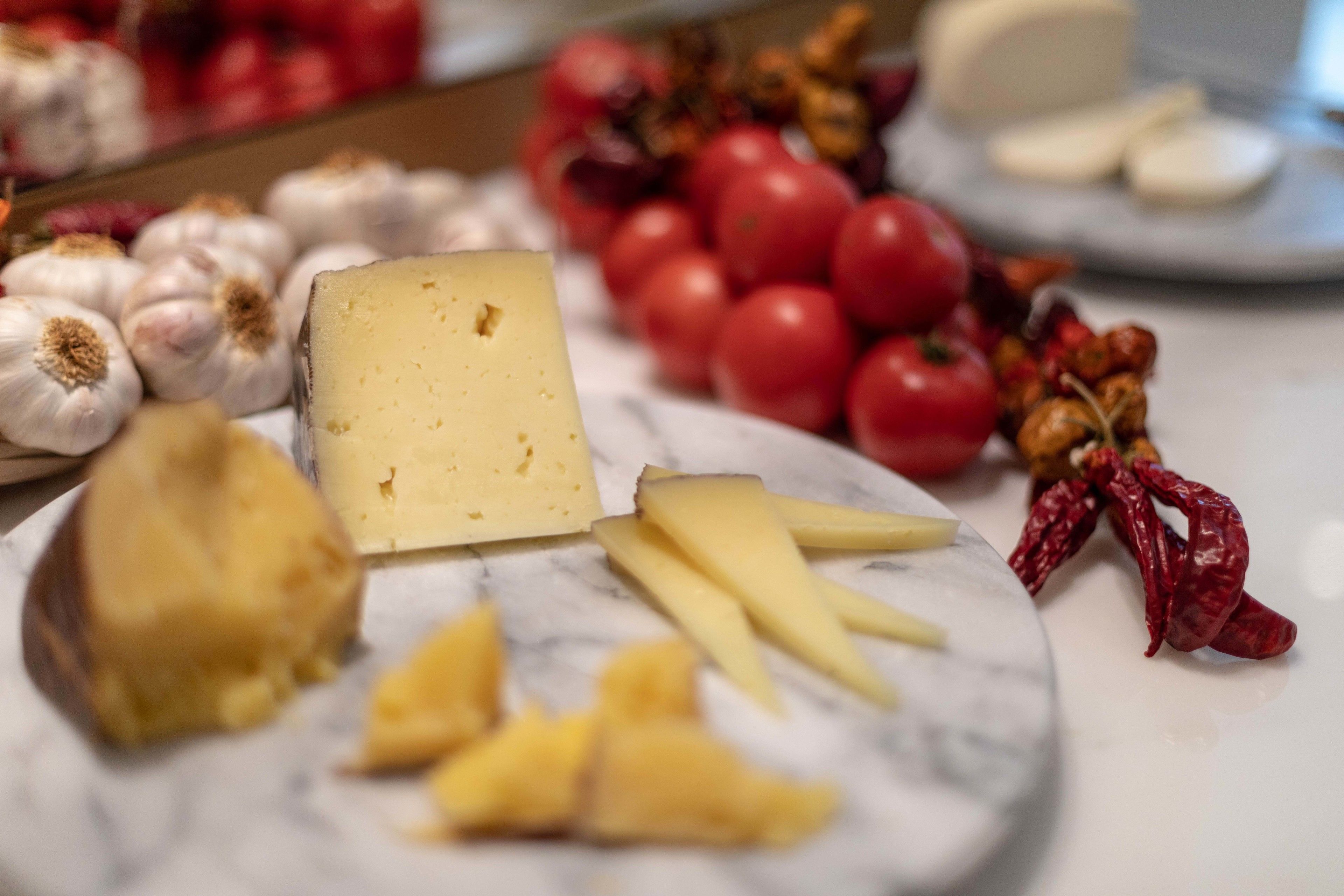 Una tabla de quesos con distintos tipos de queso y acompañamientos sobre una mesa de mármol.