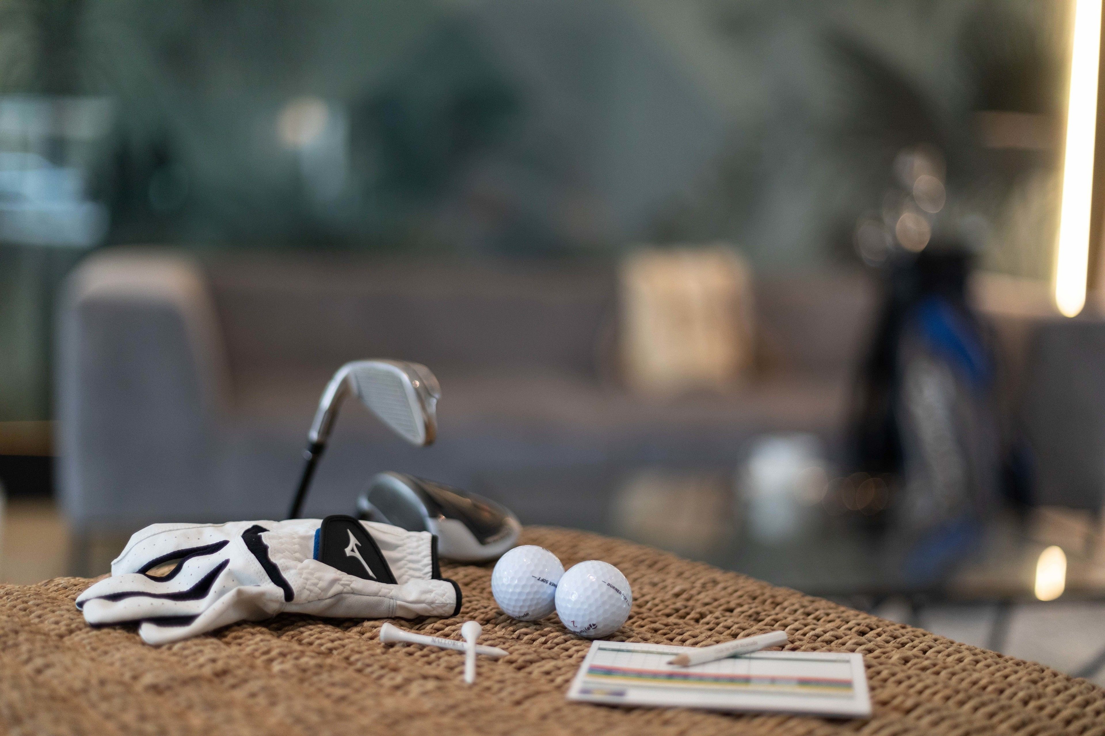 Un bolso de golf, dos pelotas de golf y un palo de golf sobre una superficie con textura.