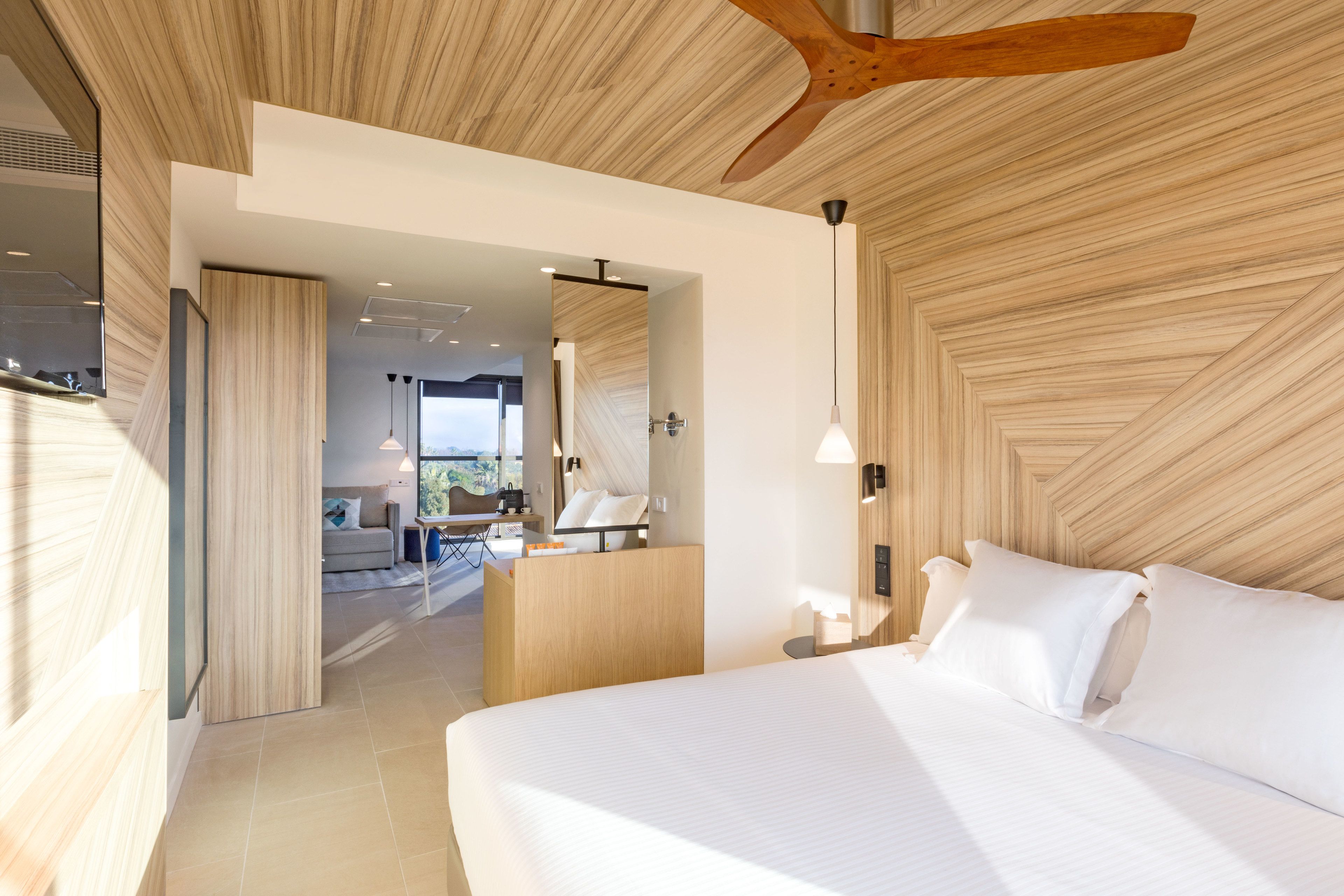 Habitación de hotel moderna con una cama grande, techo de madera y vistas al espacio exterior.