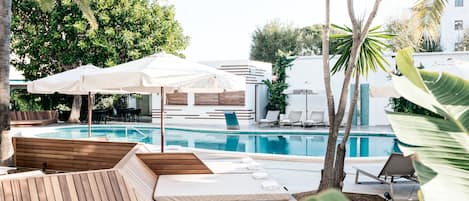 Una piscina al aire libre, sombrillas, sillones reclinables de piscina