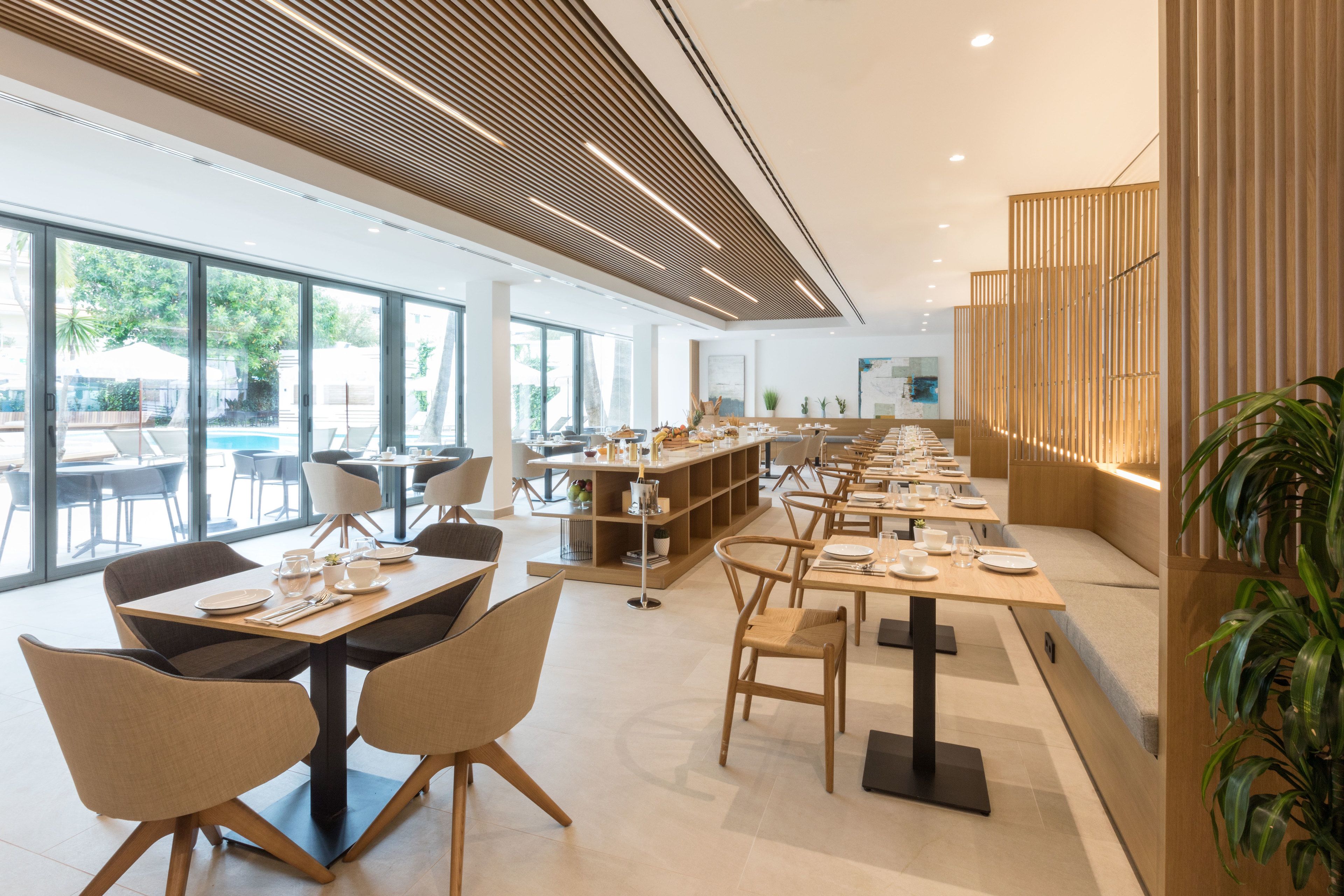 A modern dining area with long tables, chairs, and a wooden partition.