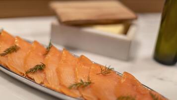 A plate of smoked salmon garnished with dill, with a wooden box and a bottle in the background.