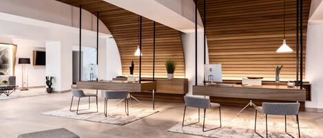 A modern reception area with a wooden ceiling, a reception desk, and two grey chairs.