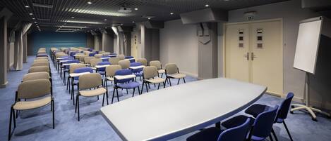 A conference room with a long table and chairs, a whiteboard, and a door with a sign.