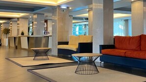 Moderni aula, jossa on vastaanottotiski, oleskelualueita ja suuri ikkuna.