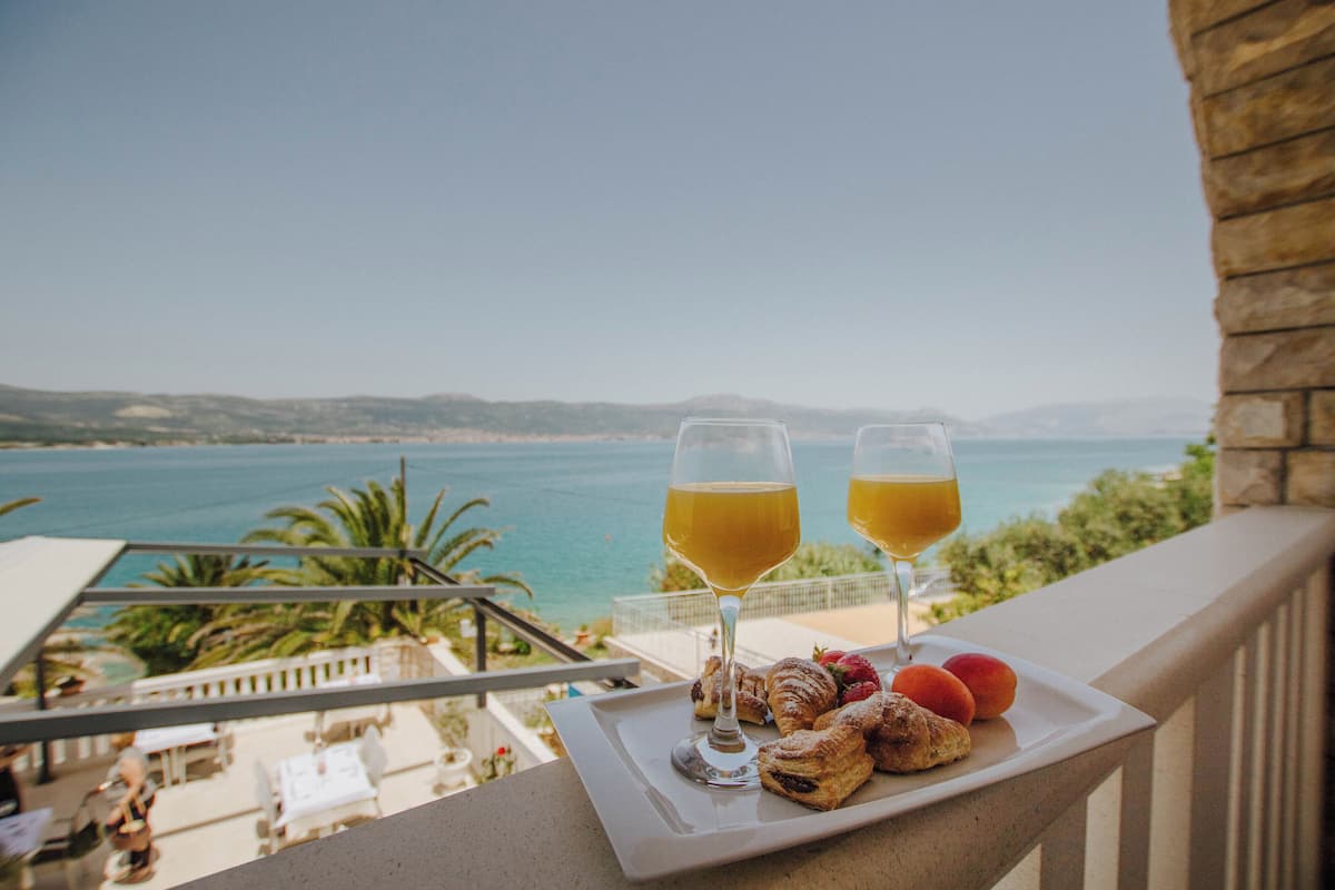 A balcony with a table set for breakfast, overlooking a coastal view.