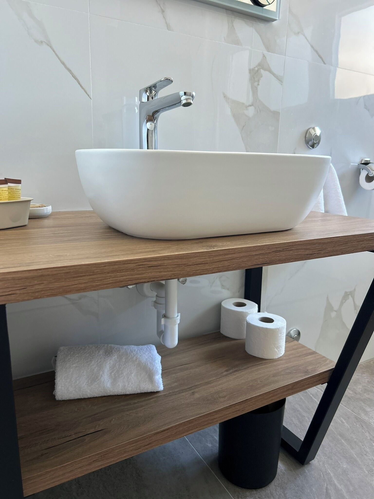 Ein modernes Badezimmer mit einem weißen Haubenspülbecken, einer Holzausziehtheke und einer Marmor-Spritzschutzwand.