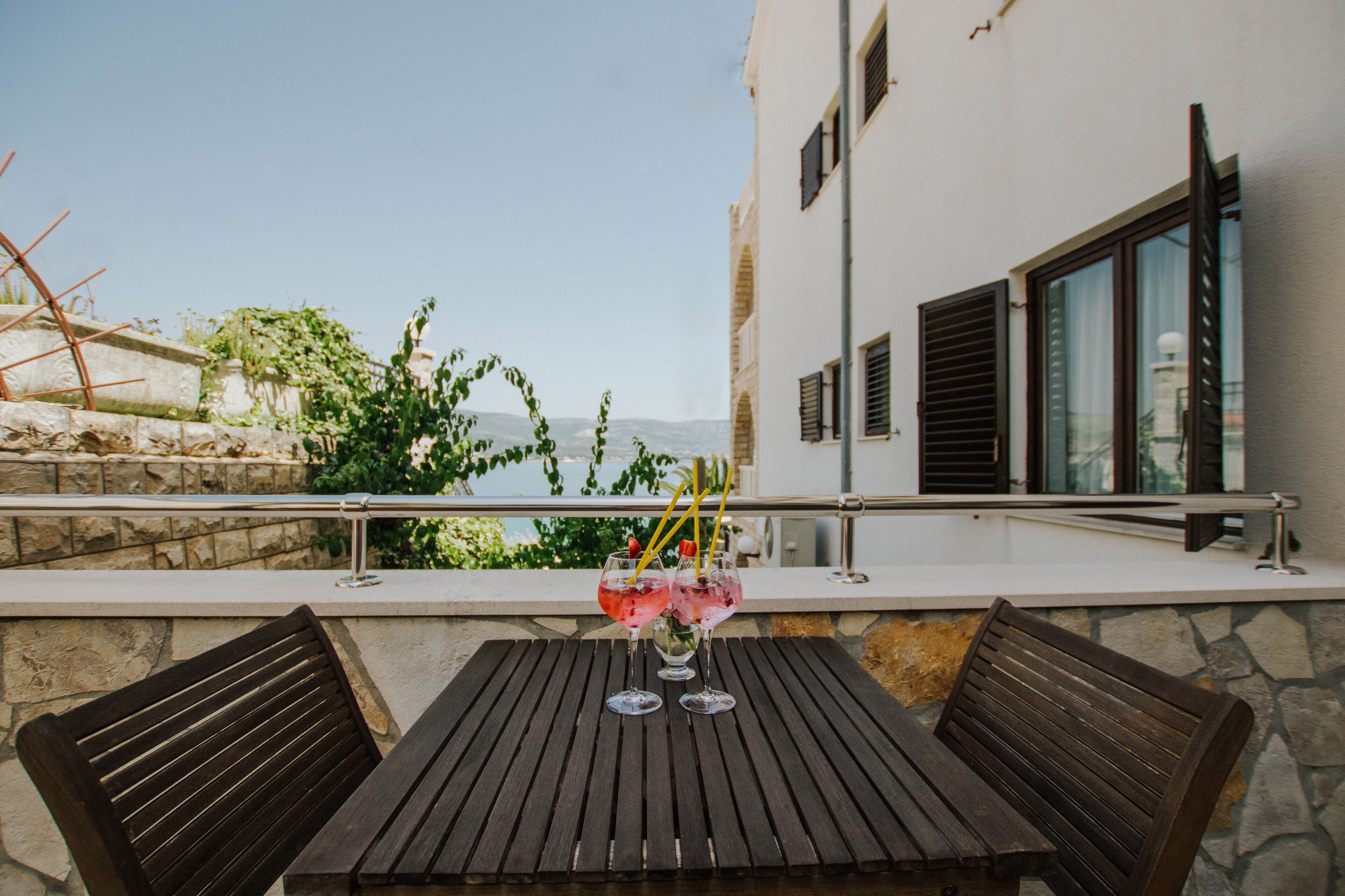 Une terrasse avec une table et deux chaises en bois, donnant sur une étendue d’eau et sur de la verdure.