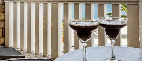 A table with two glasses of red wine, a menu, and a view of mountains in the background.