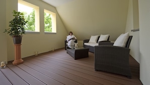 A spacious room with a large window, a potted plant, a sofa, and a coffee table. - Hotel Adlerbräu (Gunzenhausen)