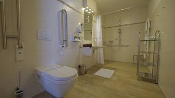 A modern bathroom with a toilet, shower, and grab bars.