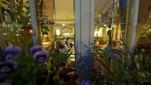 A room with a view through a window, featuring a person sitting by the window. - Hotel Adlerbräu (Gunzenhausen)