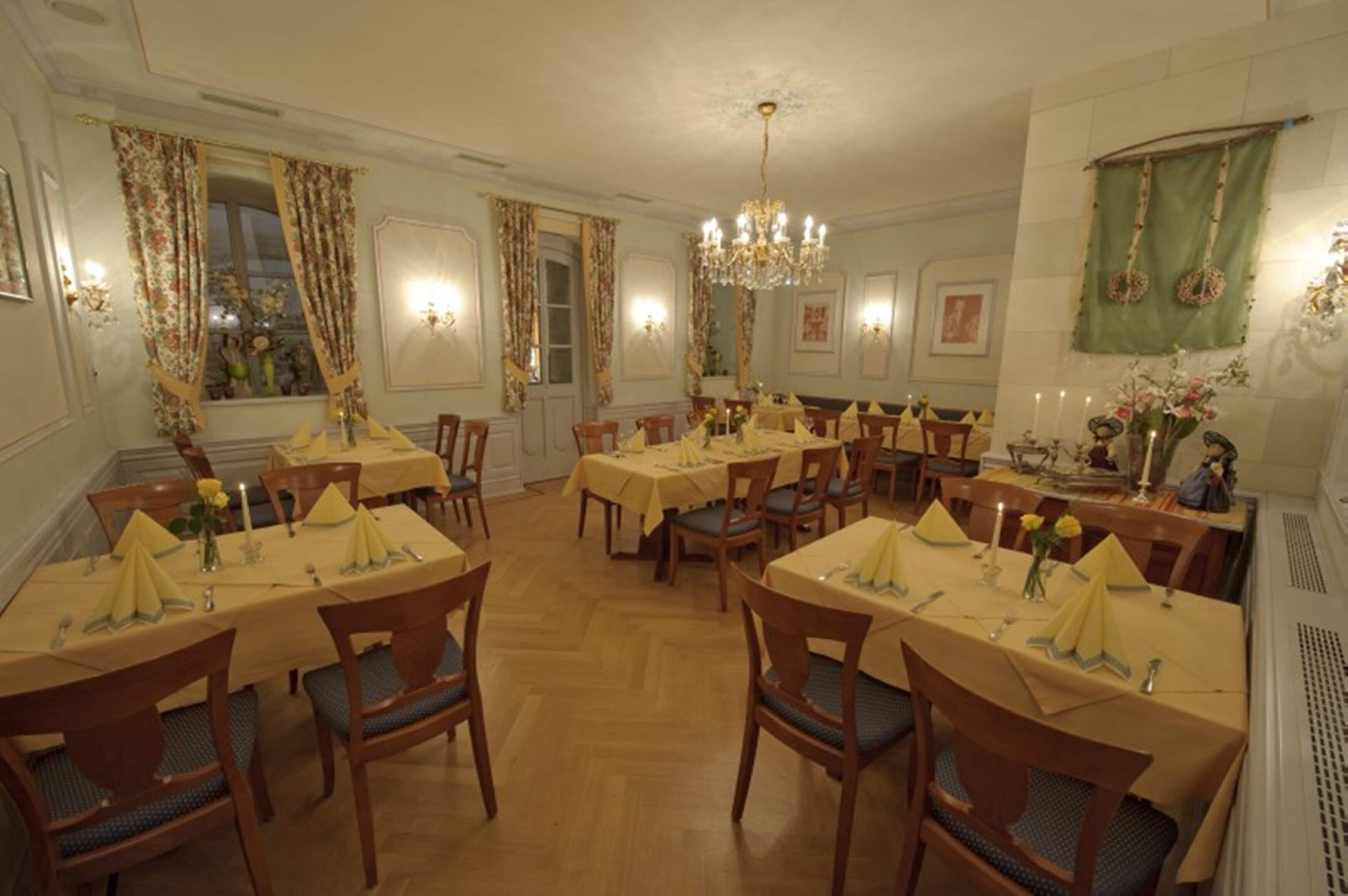 A dining area with multiple tables and chairs, each set with yellow tablecloths and napkins.