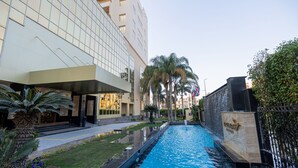 Un edificio moderno con piscina, palme e un prato curato.