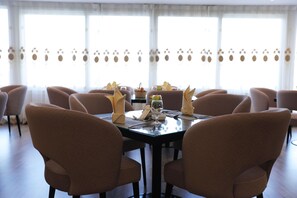 A dining area with a round table, six chairs, and a window with curtains. - Triumph Plaza Hotel (Cairo)