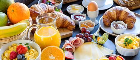 A breakfast table with various foods including fruits, pastries, and beverages.
