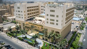 Un hotel moderno con un cortile interno, diversi piani e un cartello ben visibile.