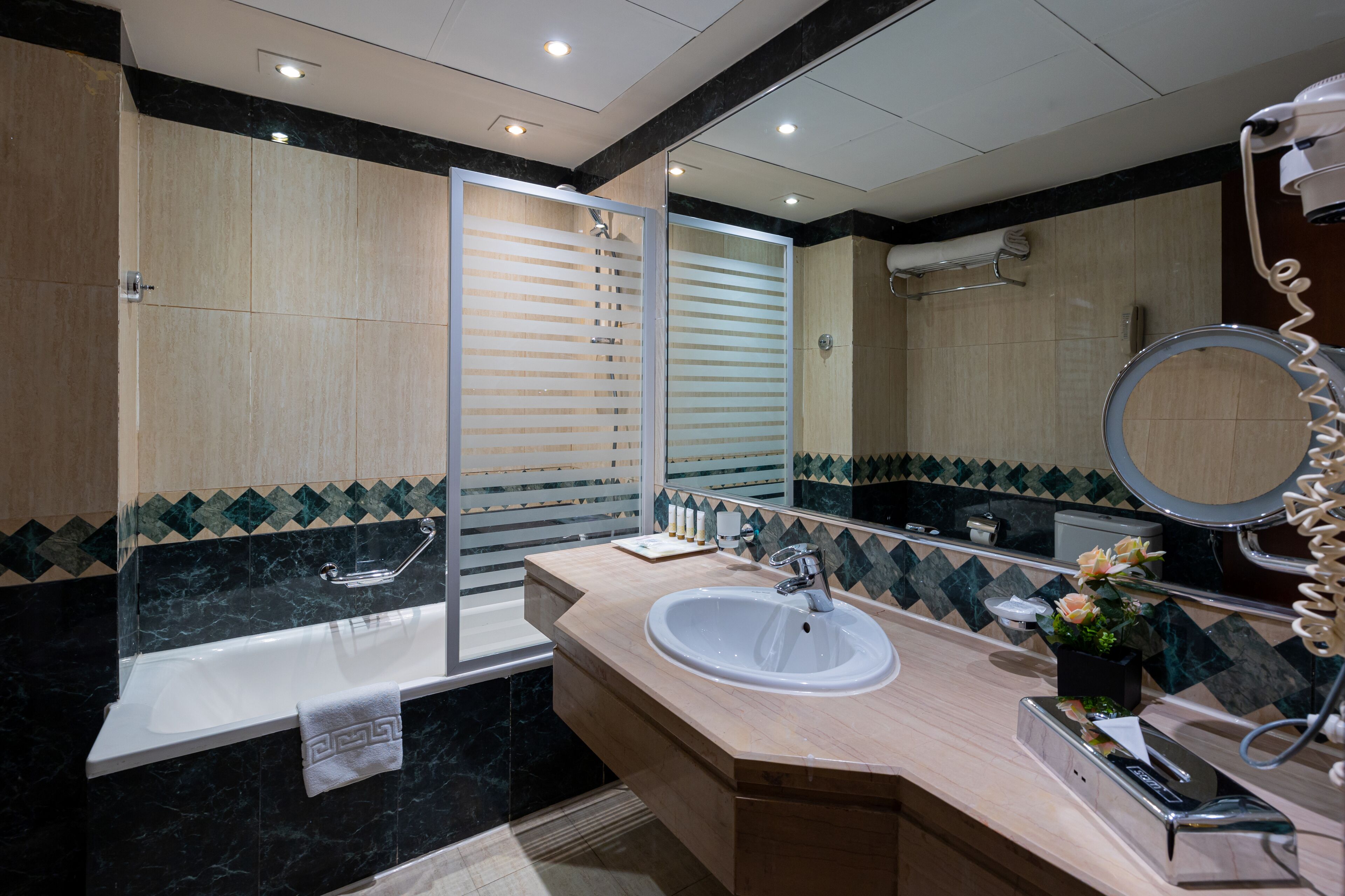 Un baño moderno con bañera, lavamanos y un espejo grande.