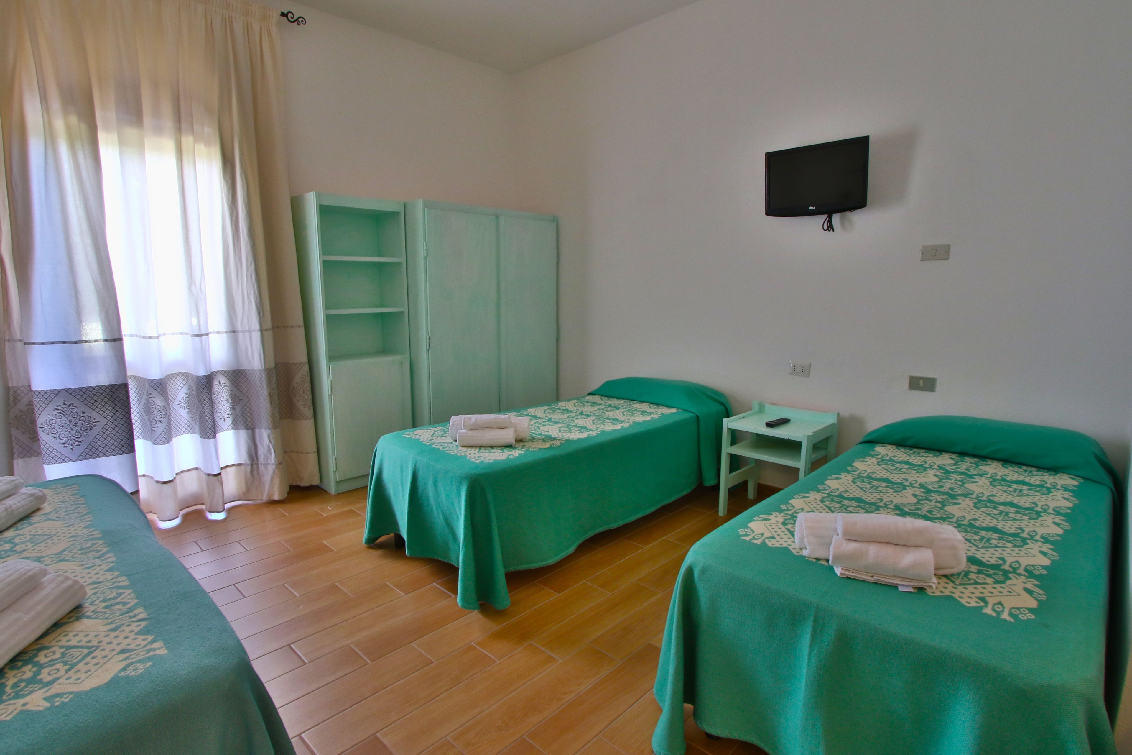 Een kamer met twee bedden, een televisie en een kledingkast.