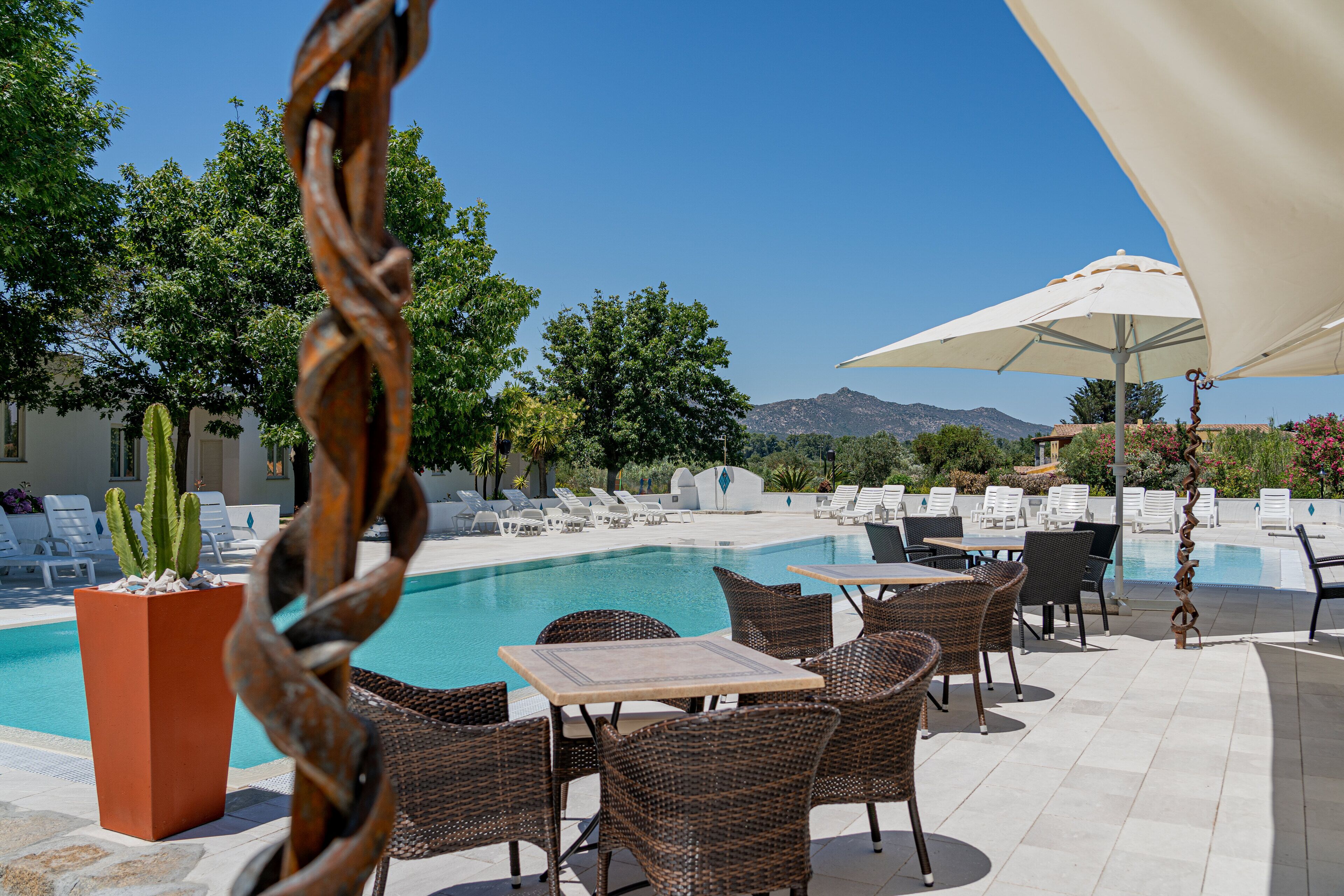 A poolside area with lounge chairs, tables, and a large umbrella.